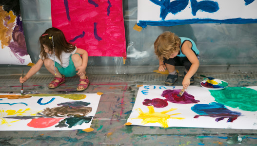 Malaktion – Auf zum Mond! Zwei Kinder malen mit Pinseln auf große Papierbögen auf dem Boden