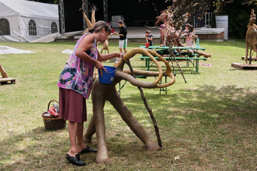 Eine Frau arbeitet an einer Skulptur aus Baumwurzeln